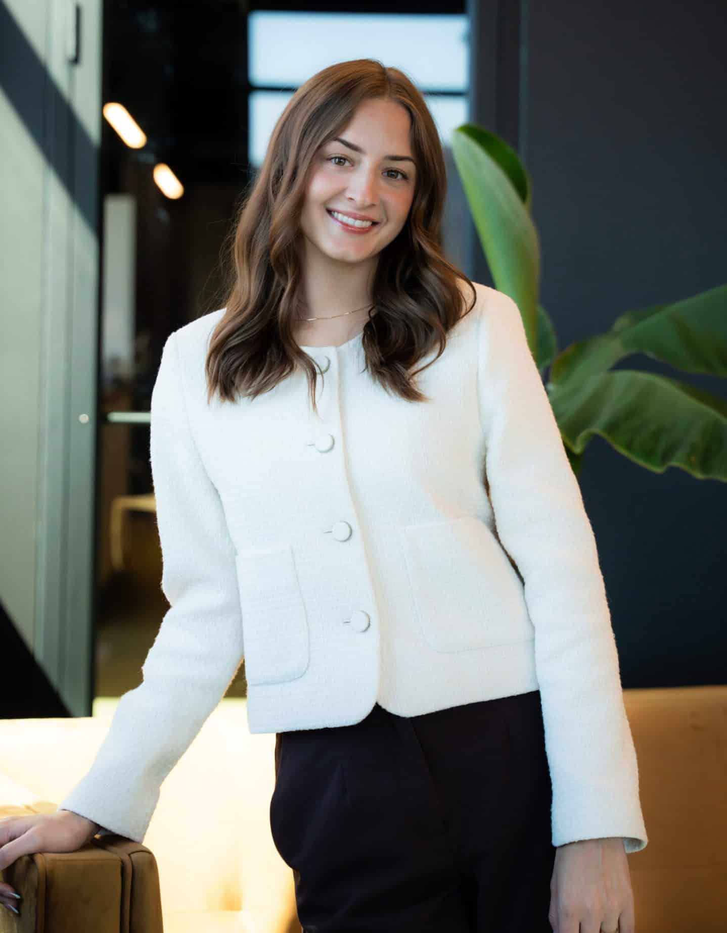 High-quality professional woman smiling in modern office environment with indoor plants.