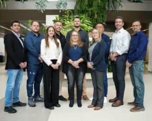 Team of diverse professionals standing together indoors at a corporate event or meeting, representing Grasslands experts.