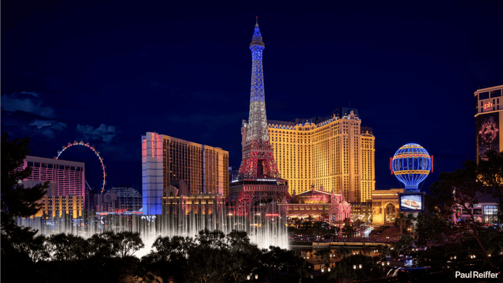 Vibrant Las Vegas cityscape at night featuring illuminated replicas of the Eiffel Tower and Paris-themed attractions.