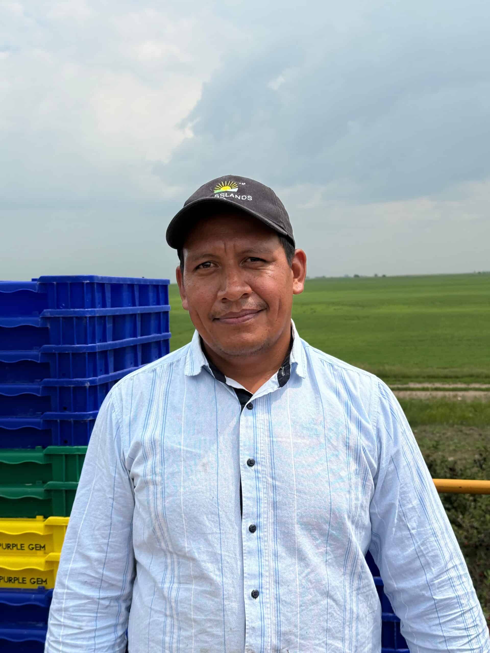 Vibrant green grassland with a smiling agricultural professional in front, emphasizing sustainable land management.